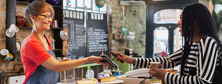 Image of a café owner taking an Apple Pay payment with an EFTPOS machine.