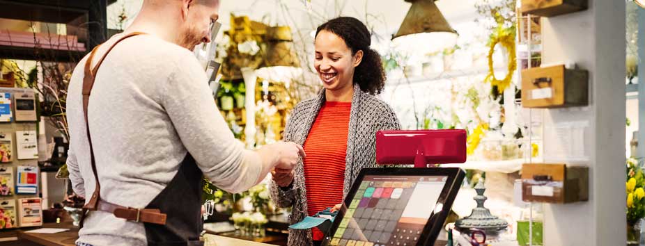 Image of a shop owner using a POS machine that integrates with her EFTPOS machine.