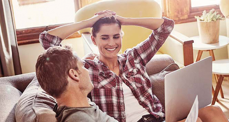 Engaged couple sitting on a couch planning their wedding together