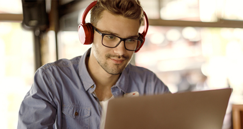 Man with glasses on a laptop while listening to a podcast about budgeting