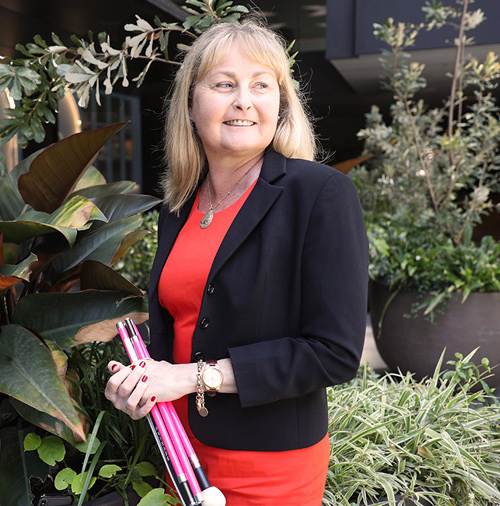 Photo of Majella Knobel, Westpac's director of access and inclusion, holding her cane, smiling towards the camera.